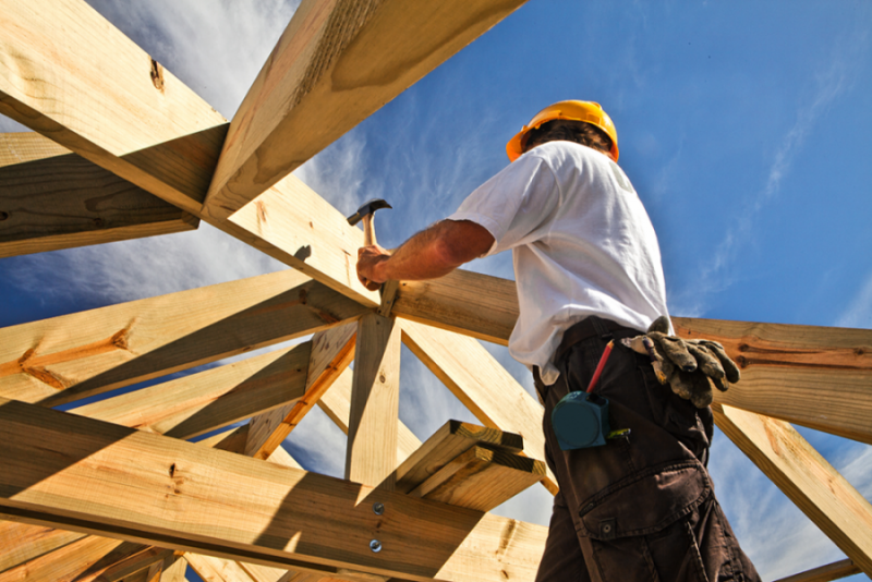 Carpenter in hard hat works on a construction site