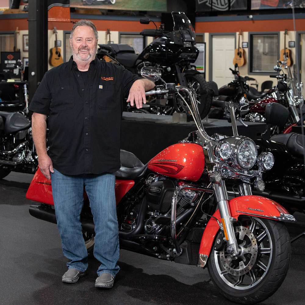 Photo of John Story Standing by a motorcycle.