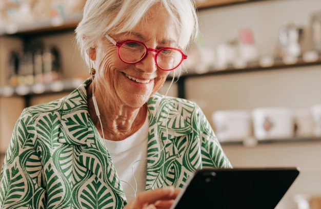 an older woman smiling while using an iPad