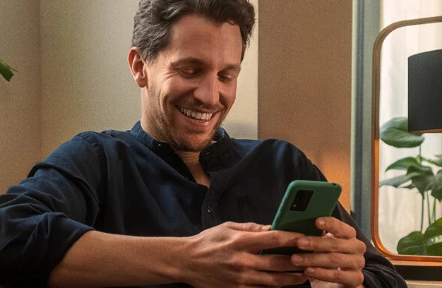 A man smiling while using his smartphone